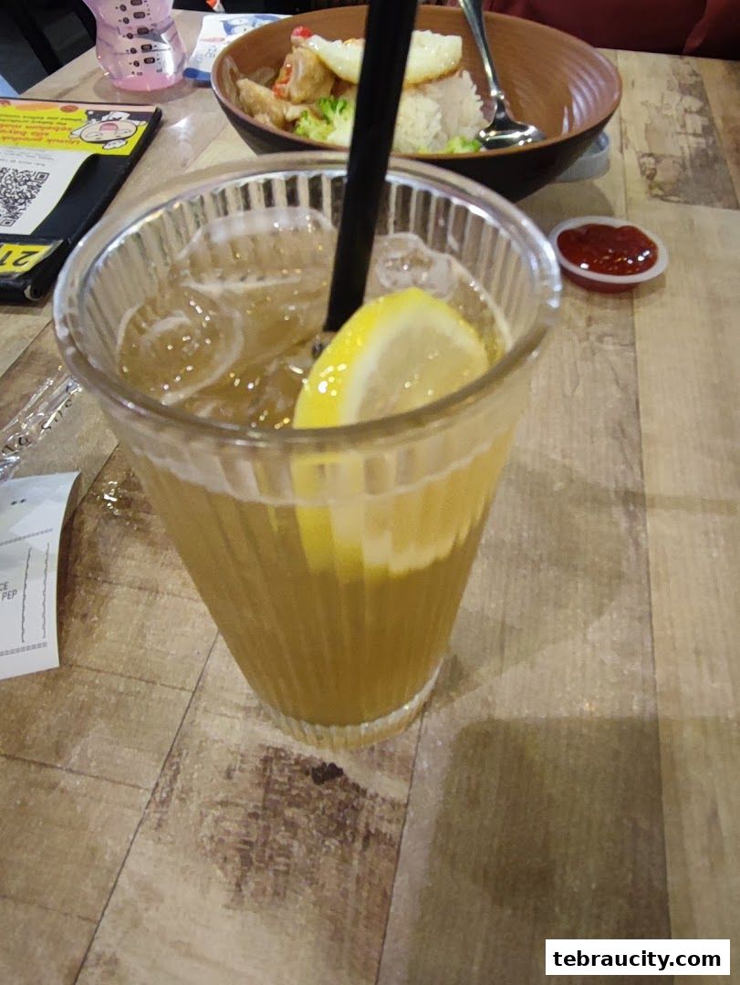 A refreshing iced tea with lemon and a side of food and ketchup.
