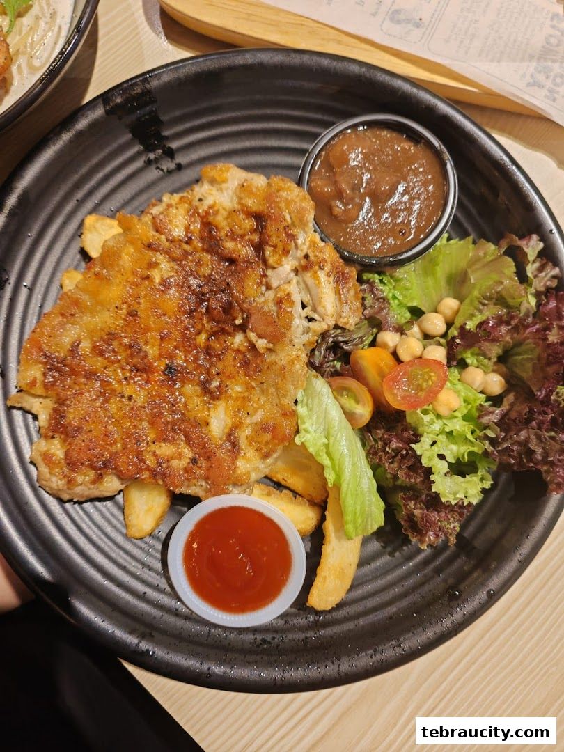A close-up of a crispy fried chicken dish with fries, salad, and dipping sauces.