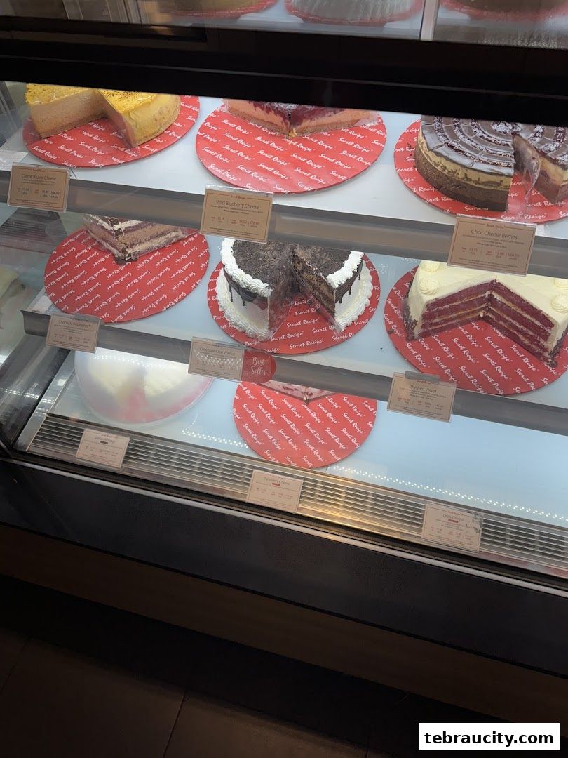 A display case filled with various cakes from Secret Recipe, showcasing different flavors and designs.
