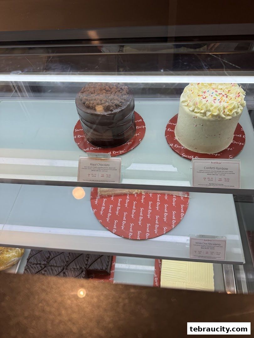 A display case filled with various cakes, including chocolate and rainbow-themed options.