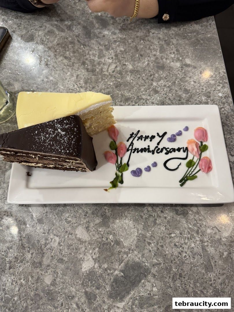 Two slices of cake and a dessert plate with 'Happy Anniversary' written on it.