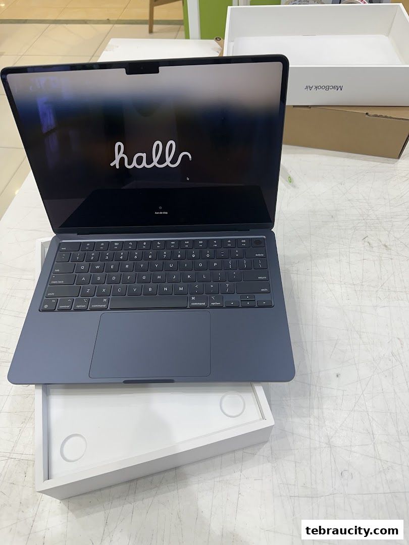 A dark blue MacBook Air laptop is open, displaying the Apple logo and setup screen.