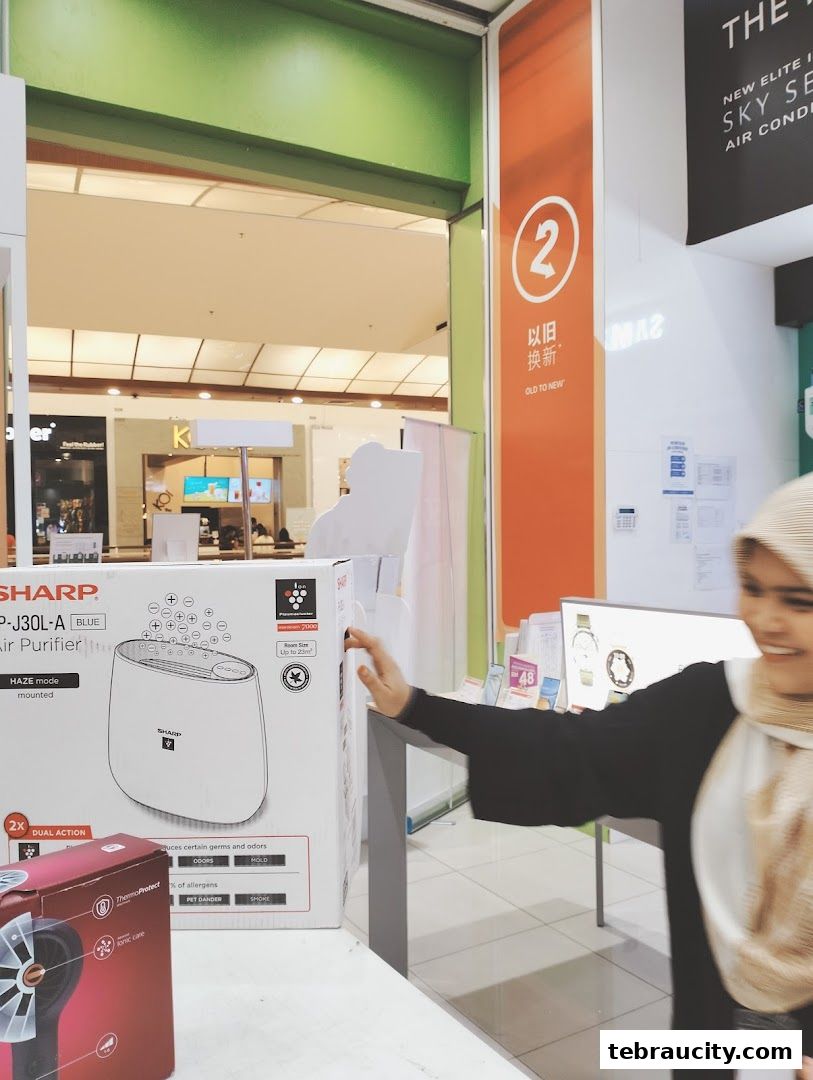 A Sharp air purifier is displayed in a retail store with a woman reaching towards it.
