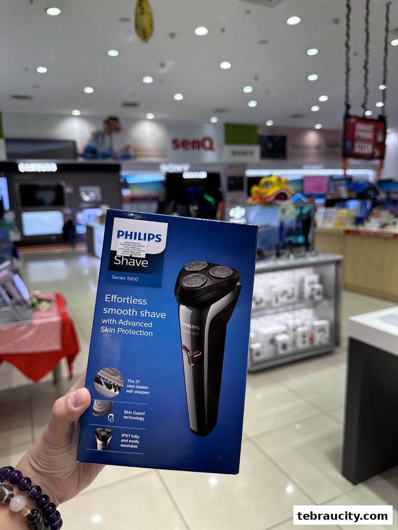 A hand holds a Philips Shave Series 1000 product box inside a senQ electronics store.
