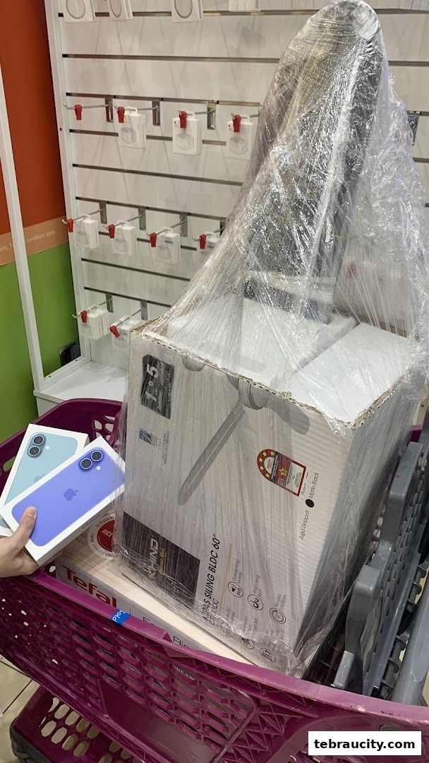 A shopping cart filled with electronics and home appliances, including iPhones and a large fan.