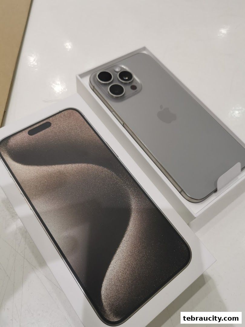 A silver iPhone 14 Pro Max phone and its box are displayed on a white surface.