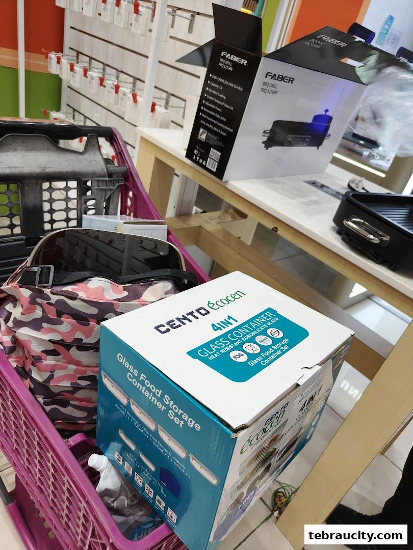 A shopping cart filled with products, including a glass food container set and BBQ grill boxes.