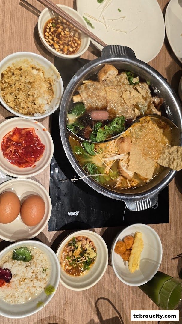 A top-down view of a hot pot meal with various side dishes and dipping sauces.