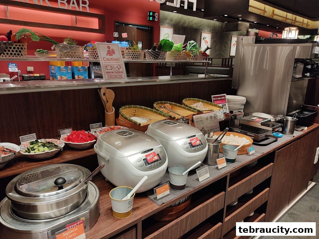 Buffet spread with rice cookers, various dishes, and a waffle maker.