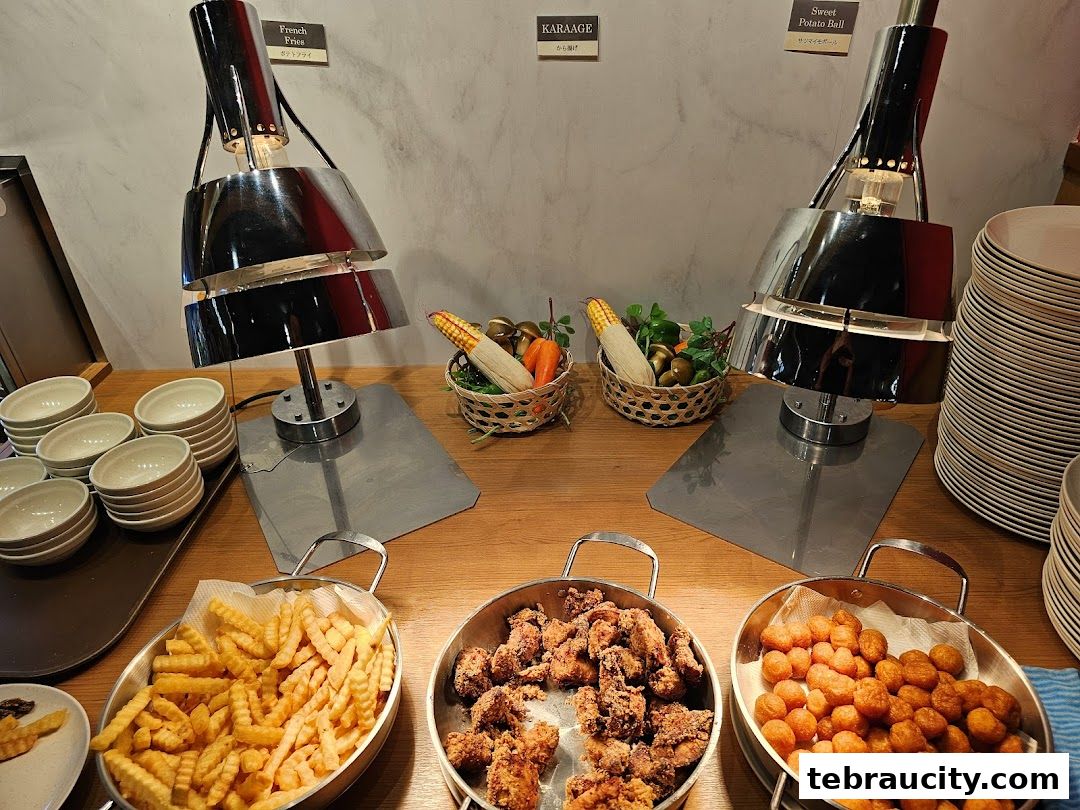A buffet spread featuring French fries, karaage, and sweet potato balls with corn and decorative elements.