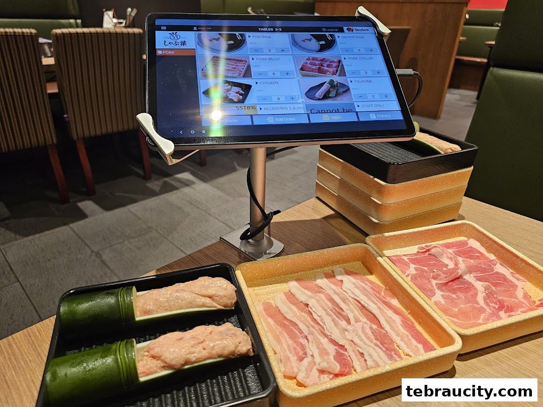 A table at Shabu-Yo with a digital menu and trays of raw meat for hot pot.