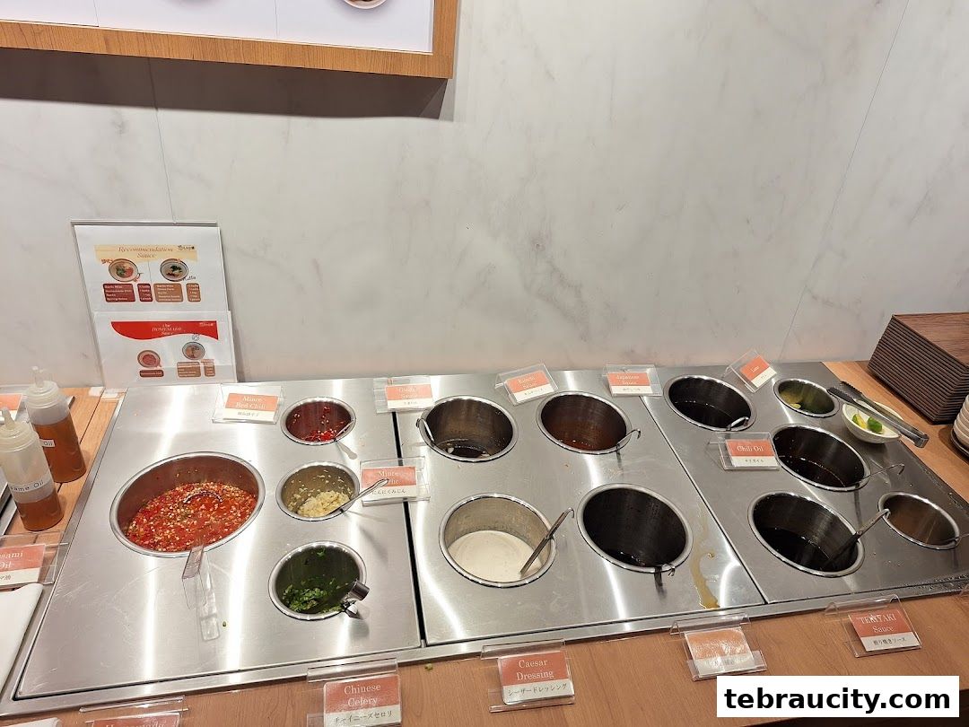 A variety of sauces and condiments are displayed in stainless steel containers for a shabu-shabu meal.