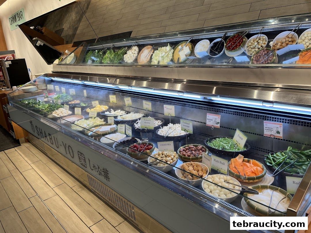 A display of fresh ingredients for shabu-shabu, including vegetables, meats, and seafood.