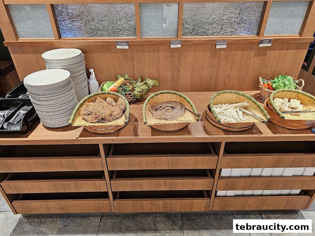 A buffet counter with various types of noodles and plates, ready for customers.