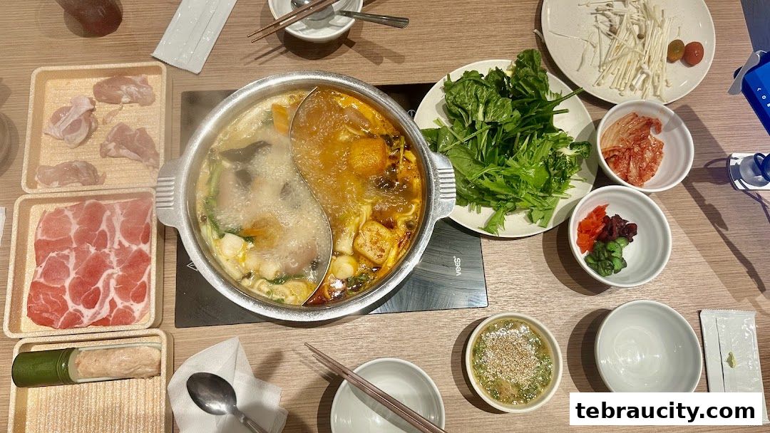 A top-down view of a hot pot meal with various ingredients and dipping sauces.