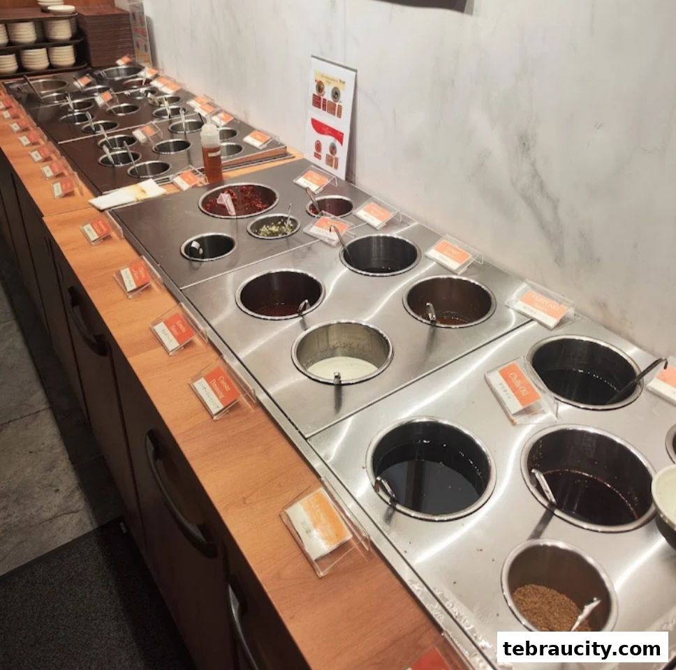 A long counter with many stainless steel containers filled with various sauces and condiments.