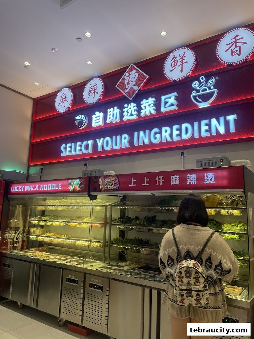 A person selects ingredients at a self-service mala noodle restaurant.