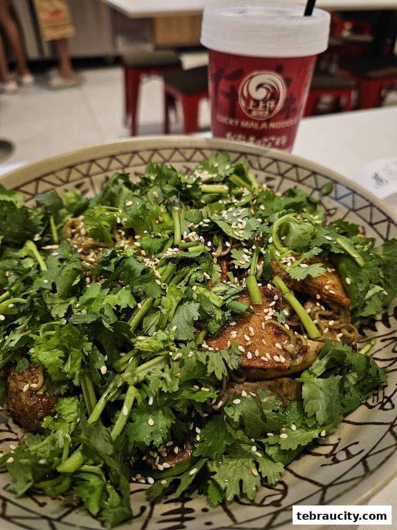 A close-up of a delicious bowl of mala noodles topped with fresh cilantro and sesame seeds.