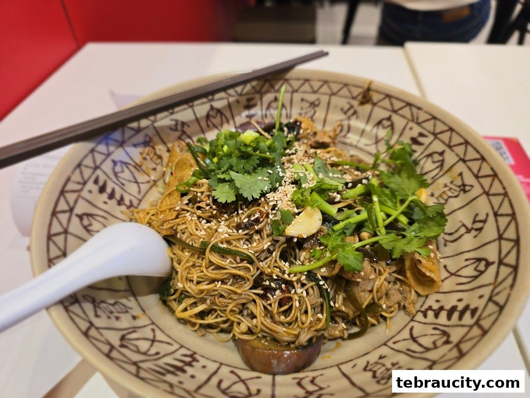 A close-up of a delicious bowl of Mala noodles with fresh herbs and sesame seeds.