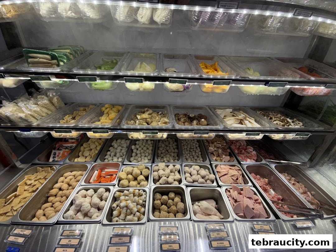 A display of various ingredients for mala hot pot, including meats, seafood, vegetables, and meatballs.