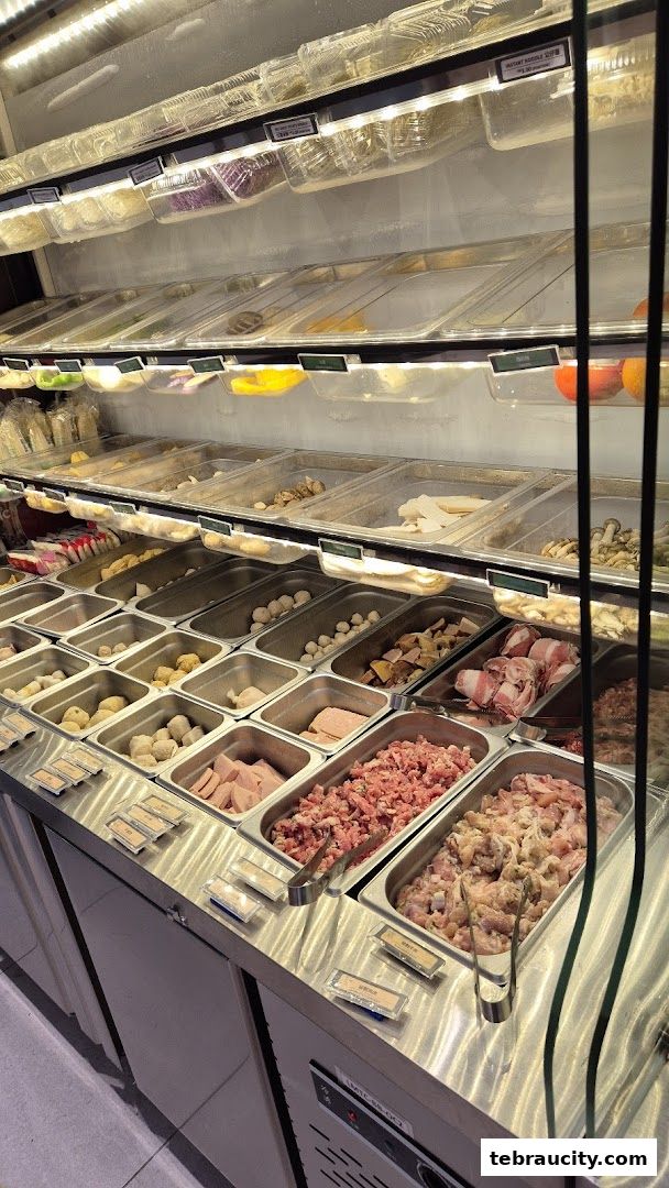 A display of fresh ingredients for mala hot pot, including meats, vegetables, and meatballs.