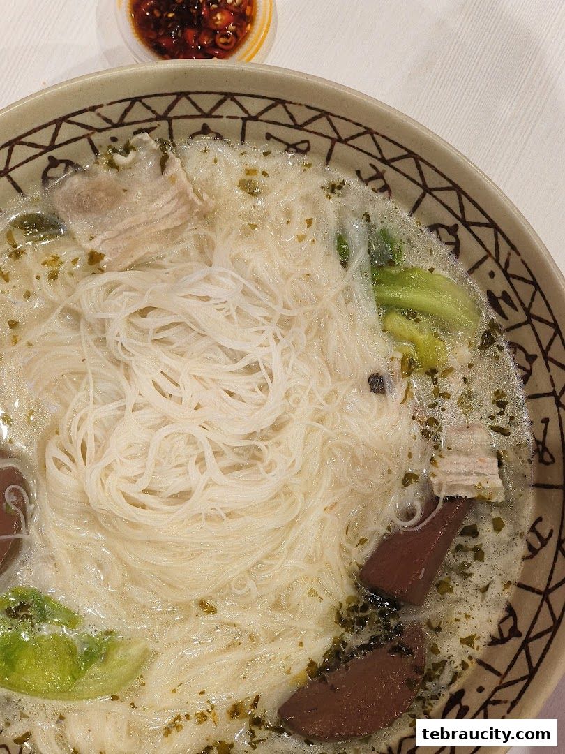 A close-up shot of a bowl of mala noodles with meat and vegetables, served with chili oil.