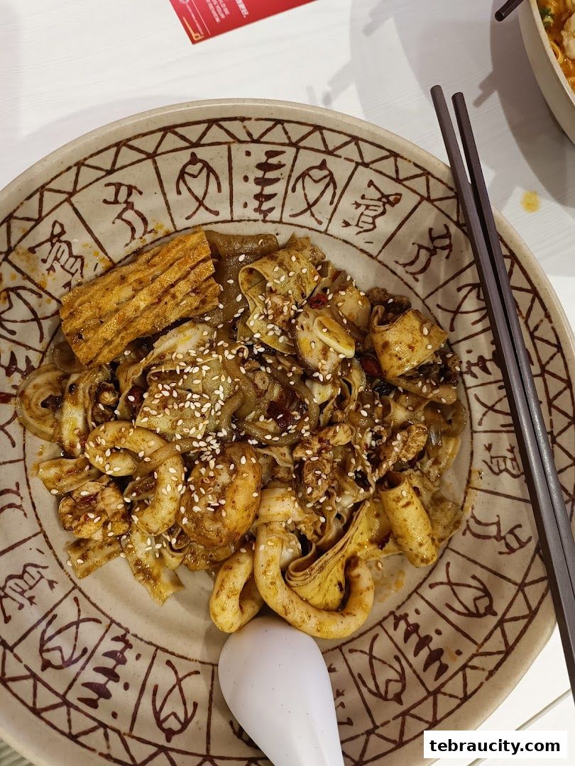 A close-up of a bowl of spicy mala noodles with shrimp and tofu skin.