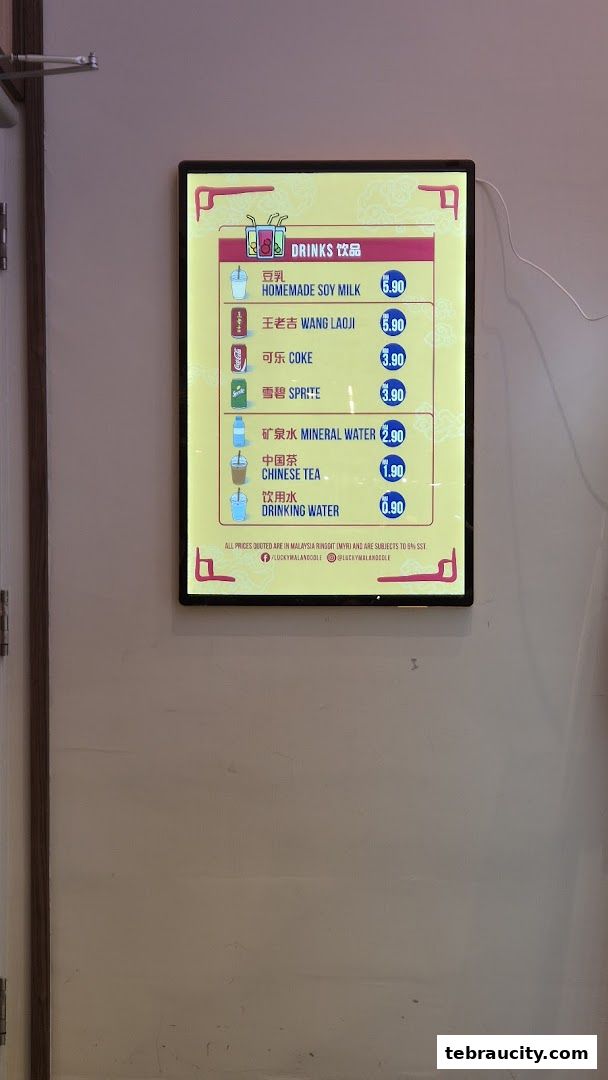 A digital menu board displaying various drinks and their prices at Lucky Mala Noodle.