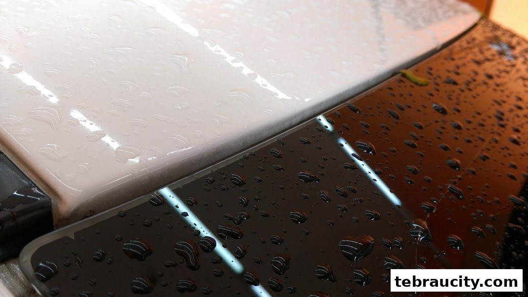 Close-up of water droplets on a glossy surface, with reflections of lights.