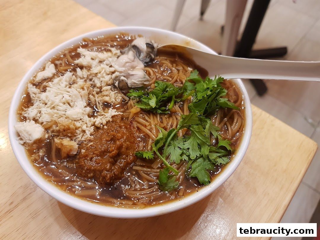 A close-up shot of a delicious bowl of Taiwanese oyster mee sua with shredded chicken and chili paste.