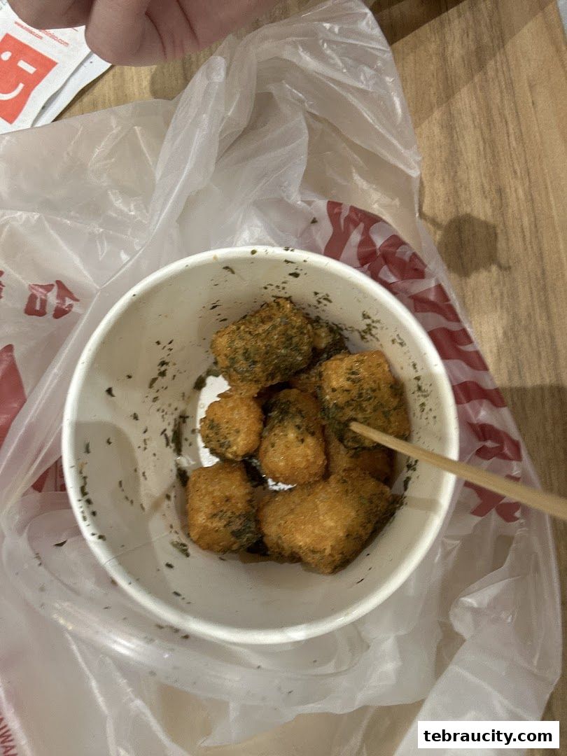 A bowl of fried Taiwanese snacks with a skewer, presented in a plastic bag.