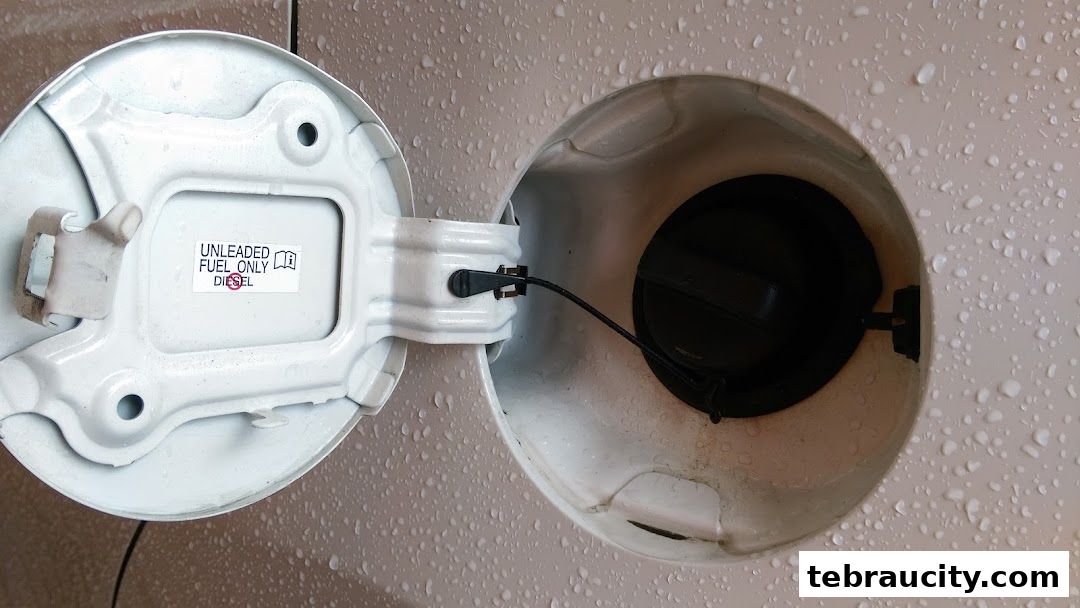 A car's open fuel filler cap with a sticker indicating unleaded fuel only.