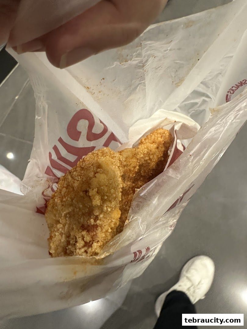 A person holding a bag of crispy fried chicken snacks from Shihlin Taiwan Street Snacks.