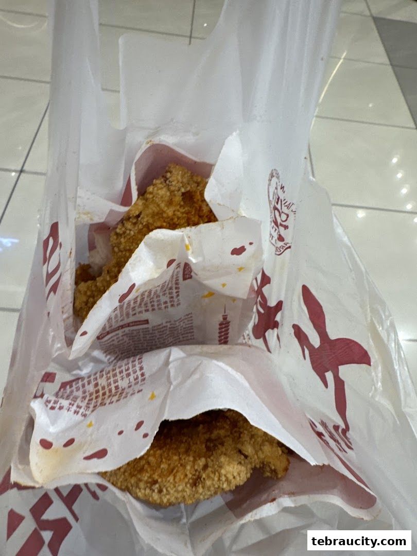 A white paper bag filled with crispy fried chicken pieces from Shihlin Taiwan Street Snacks.