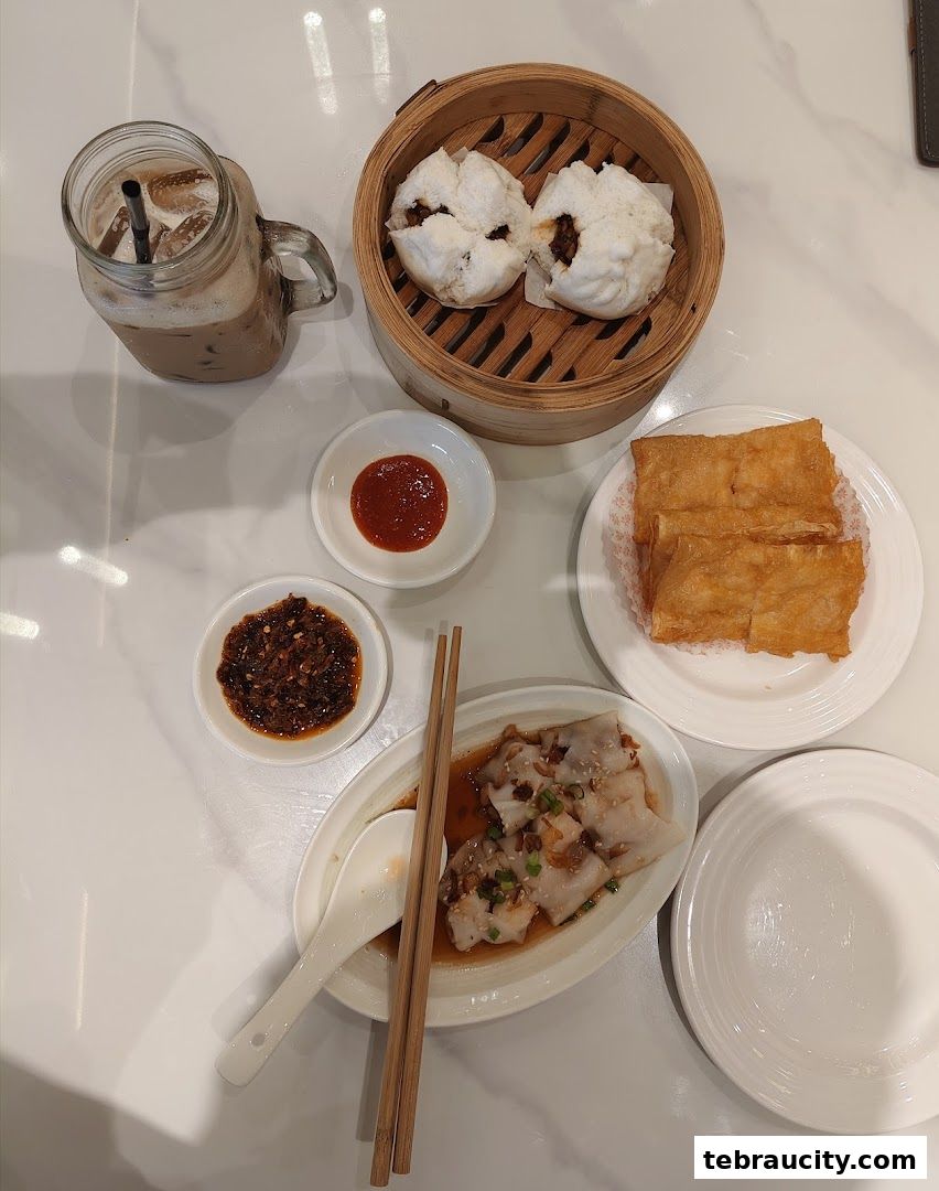 A table laden with delicious dim sum dishes and a refreshing iced drink.