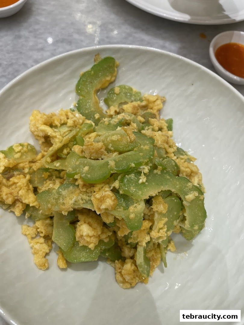 A close-up shot of bitter gourd stir-fried with scrambled eggs in a white bowl.