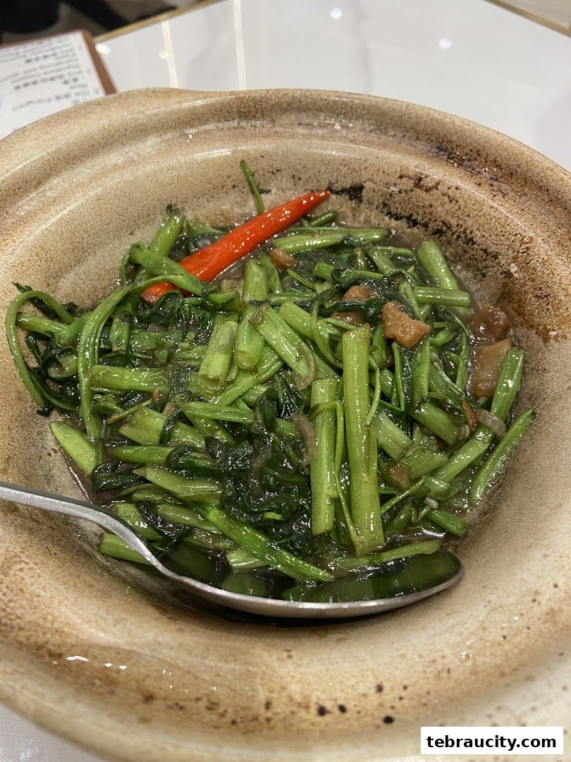 A close-up shot of stir-fried water spinach with chili and garlic in a clay pot.