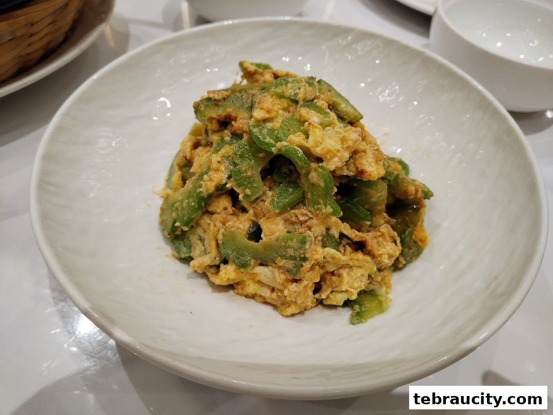 A close-up shot of bitter gourd stir-fried with eggs in a white bowl.
