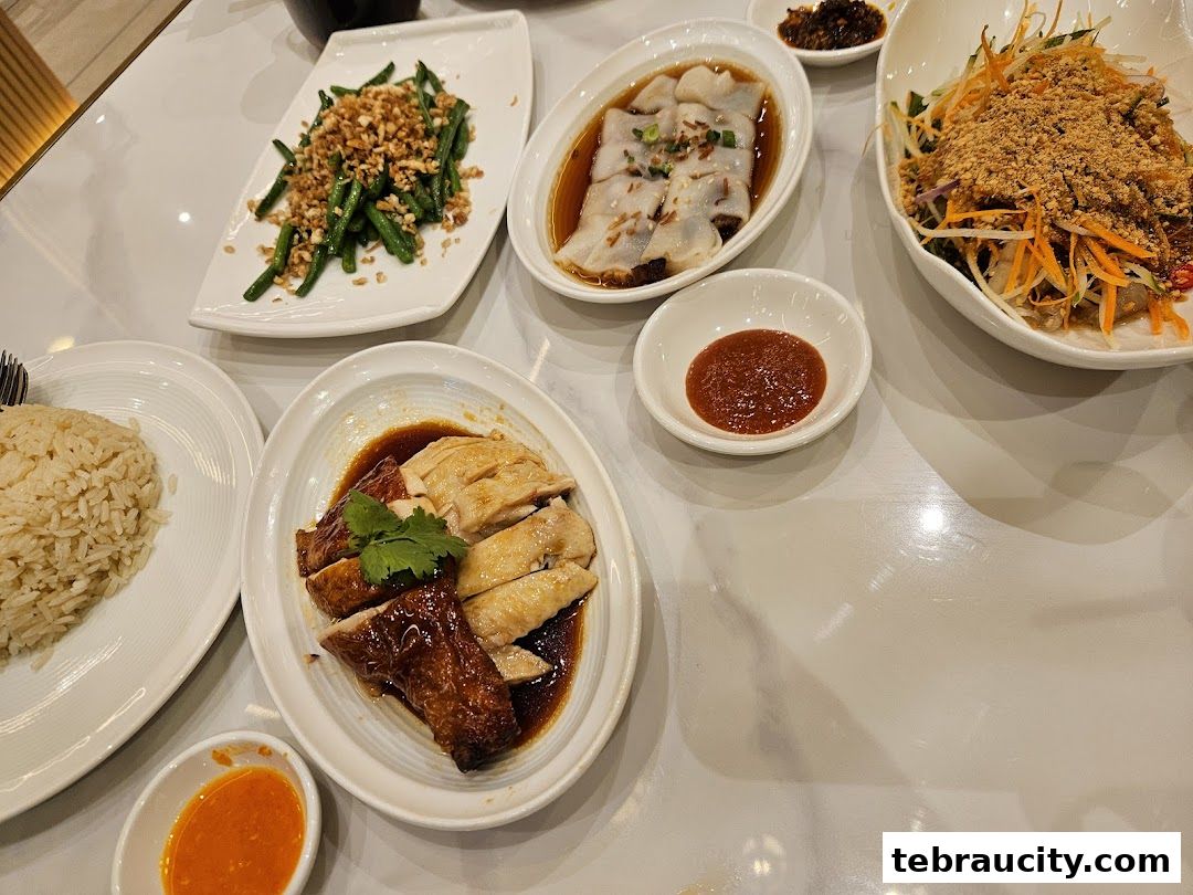 A table laden with delicious Hainanese chicken rice and various side dishes.