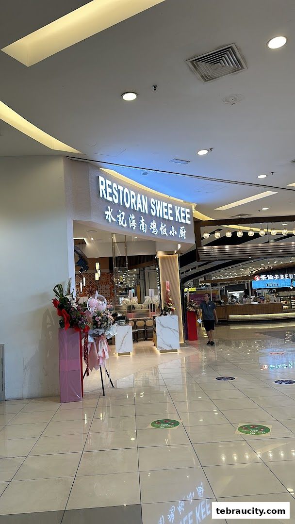 The entrance of Restoran Swee Kee, a Hainanese chicken rice restaurant, decorated with floral arrangements.