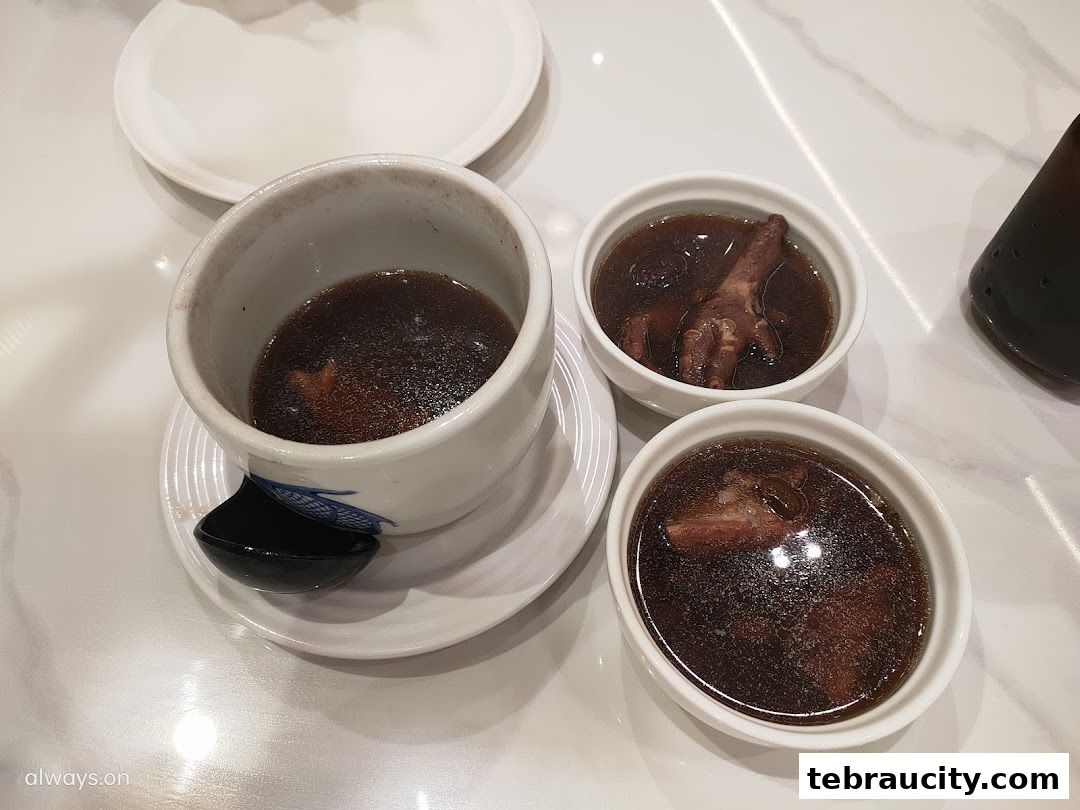 Three bowls of savory soup with chicken feet and meat, served at a restaurant.