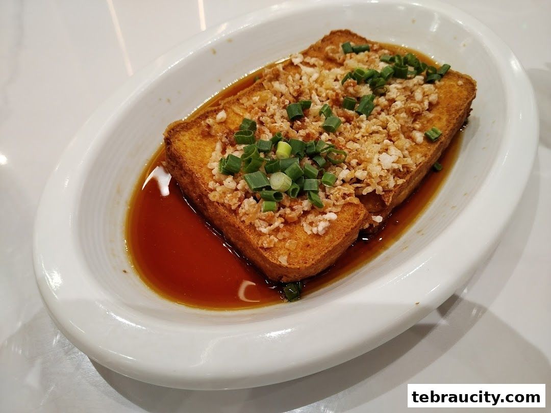 A close-up shot of a delicious fried tofu dish topped with minced garlic and spring onions.