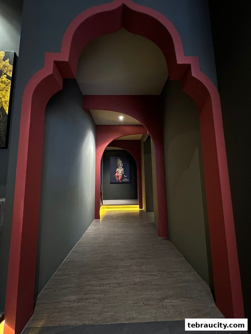 A dimly lit hallway with arched doorways and artwork, leading into the shop.