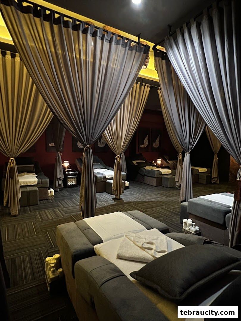 Interior view of a spa with multiple massage beds separated by elegant curtains.
