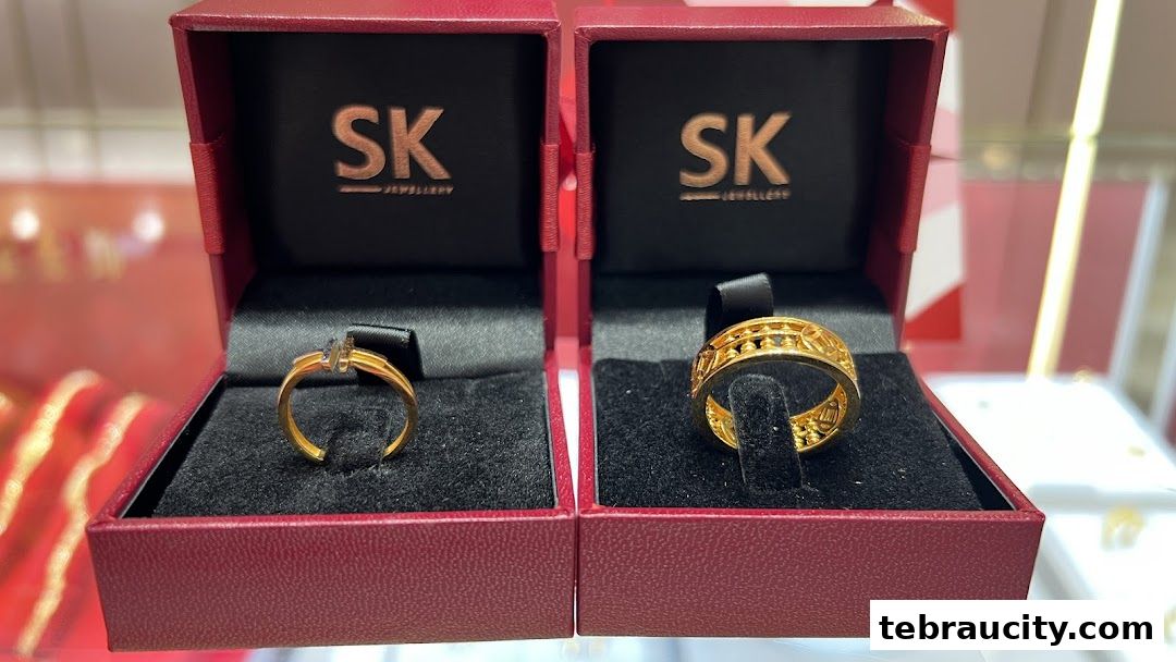 Two gold rings displayed in open red jewelry boxes with the SK Jewellery logo.