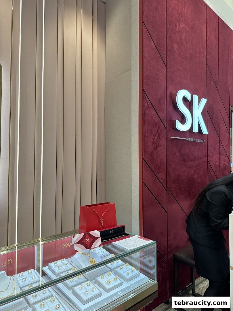 SK Jewellery shop interior with display cases filled with gold jewelry and a red branded shopping bag.