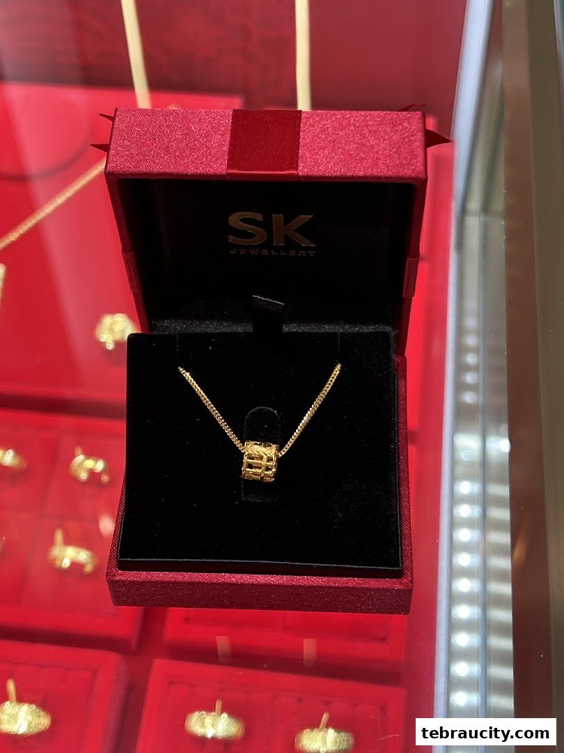 A gold pendant necklace displayed in an open red jewelry box.