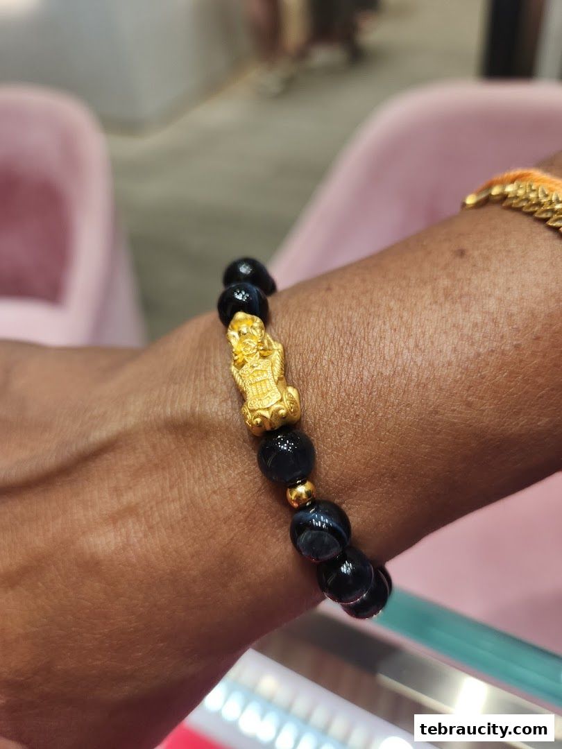 A close-up of a bracelet with black beads and a gold charm on a wrist.