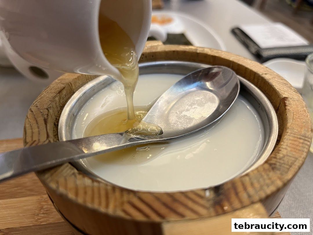 A close-up shot of a dessert being prepared, with a clear liquid being poured over a white base.