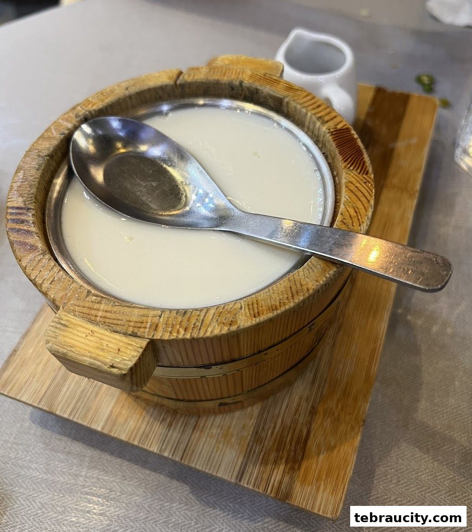 A close-up of a creamy dessert served in a wooden bucket with a spoon.